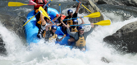 rafters holding up paddles in rapid