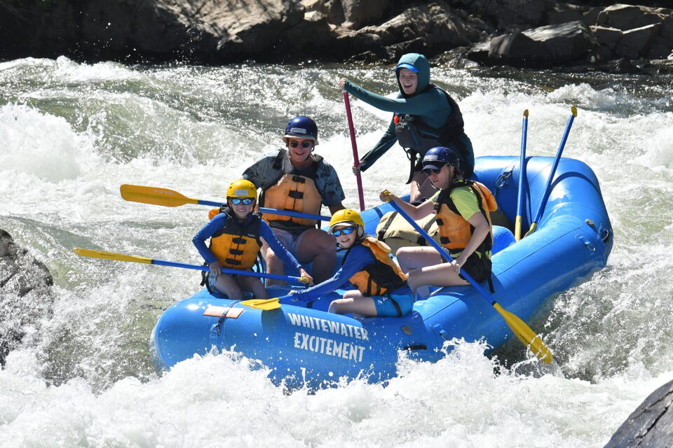 family rafting south fork american river with kids sitting in the front and parents in the back