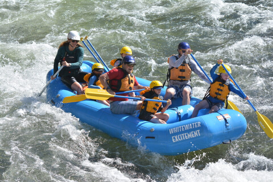 Young kids aged 5-8 smiling as they raft with their family on the south fork of the american river