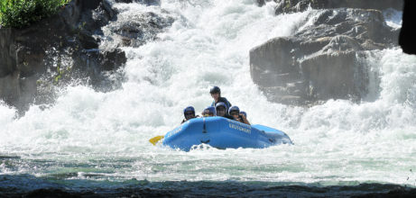rafters sitting down in rafts in a rapid