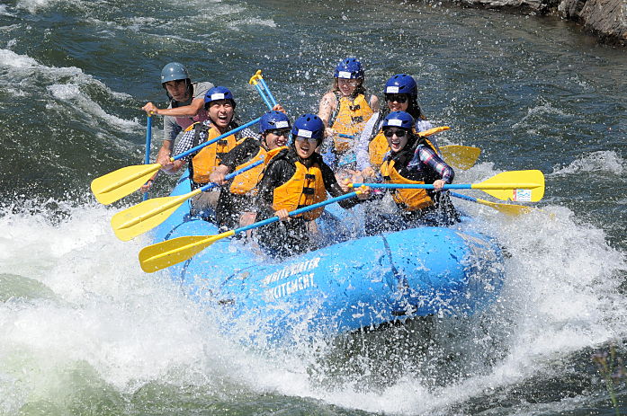 photo of people on blue raft going through rapids whitewater rafting